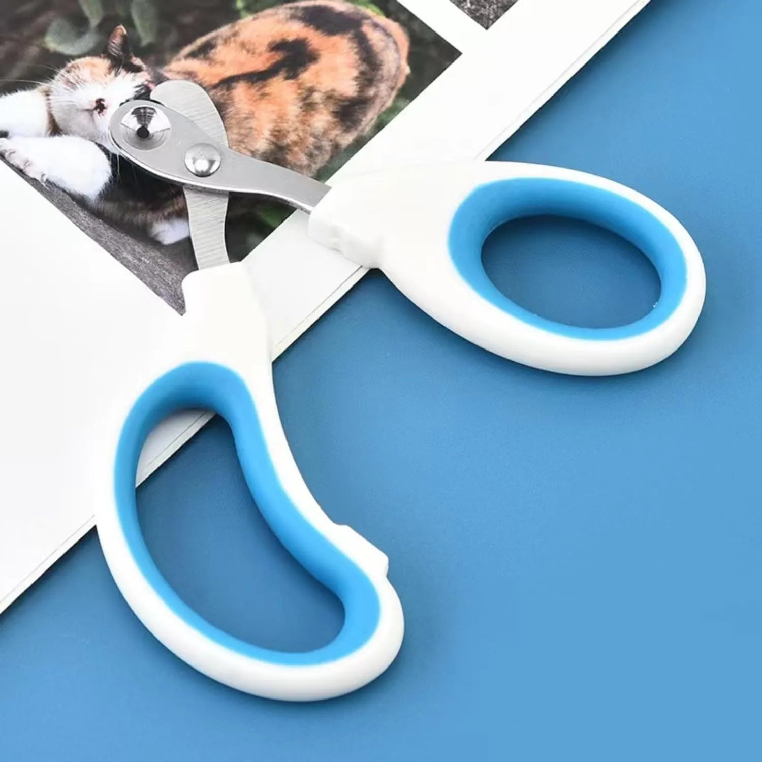 Blue pet nail clippers with circular cut hole and non-slip handles on a white background.