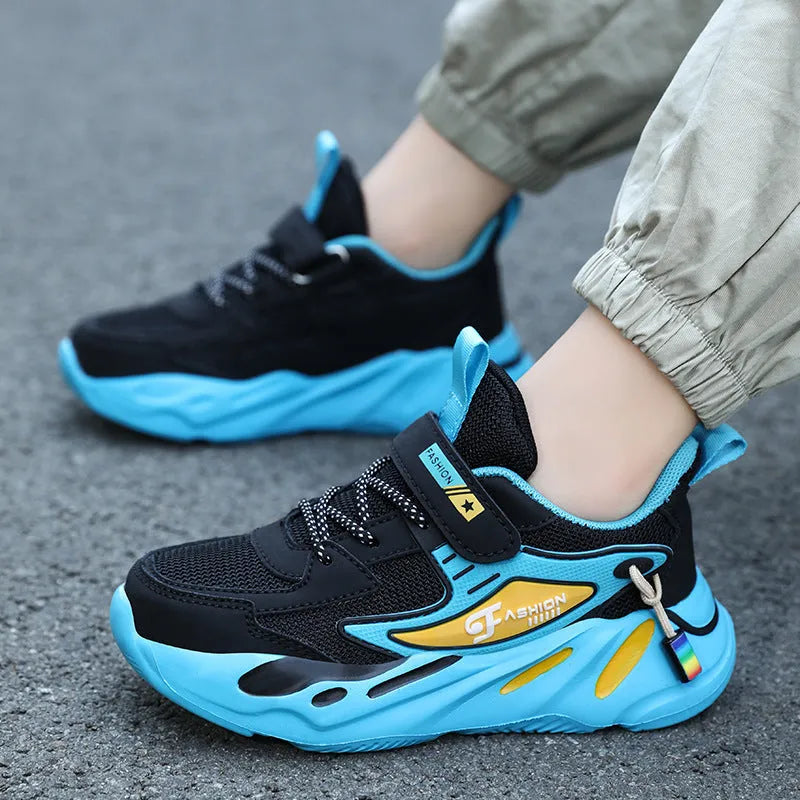 Boy's blue sports running shoe with velcro strap and mesh upper on a hard ground surface.
