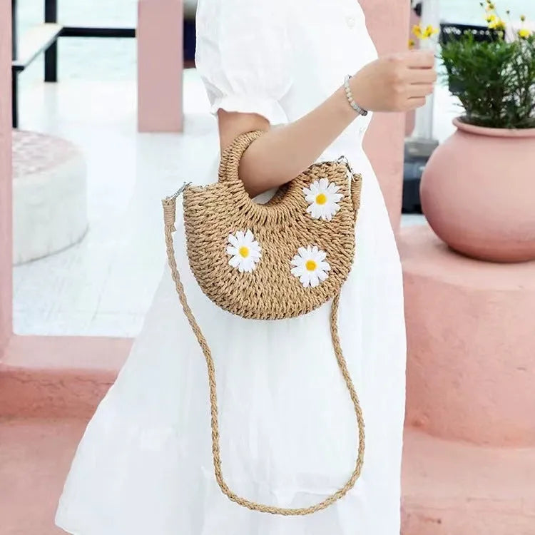 Light brown straw-weaved women's crossbody bag with daisy pattern, showing woven texture and crossbody strap