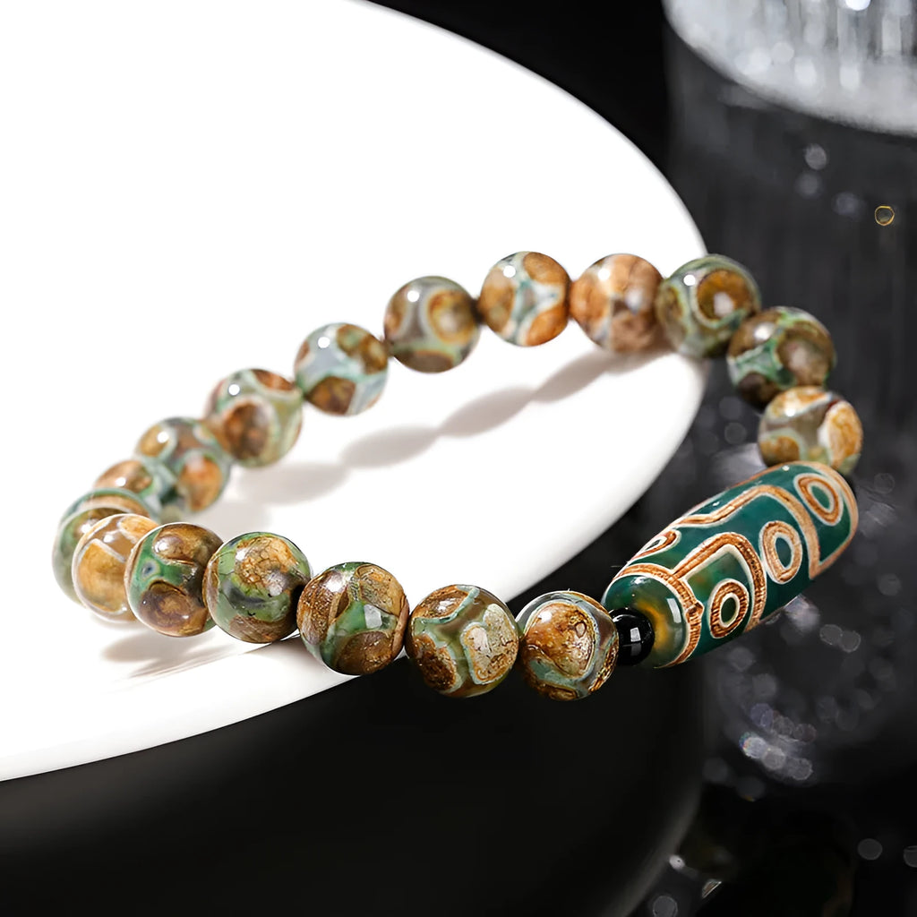 Handmade green dzi bead barrel bracelet with 8mm round geometric beads on a wrist.
