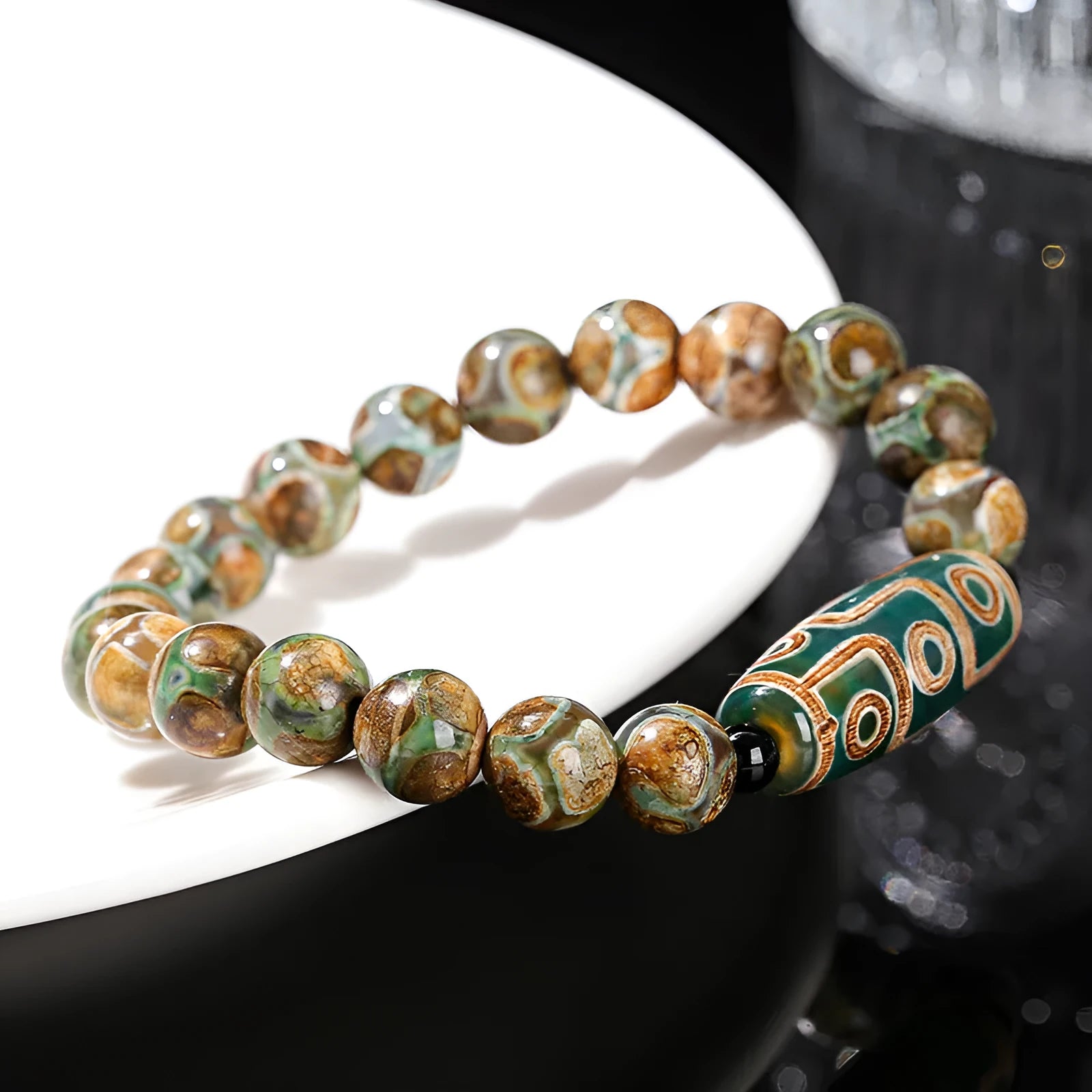 Handmade green dzi bead barrel bracelet with 8mm round geometric beads on a wrist.