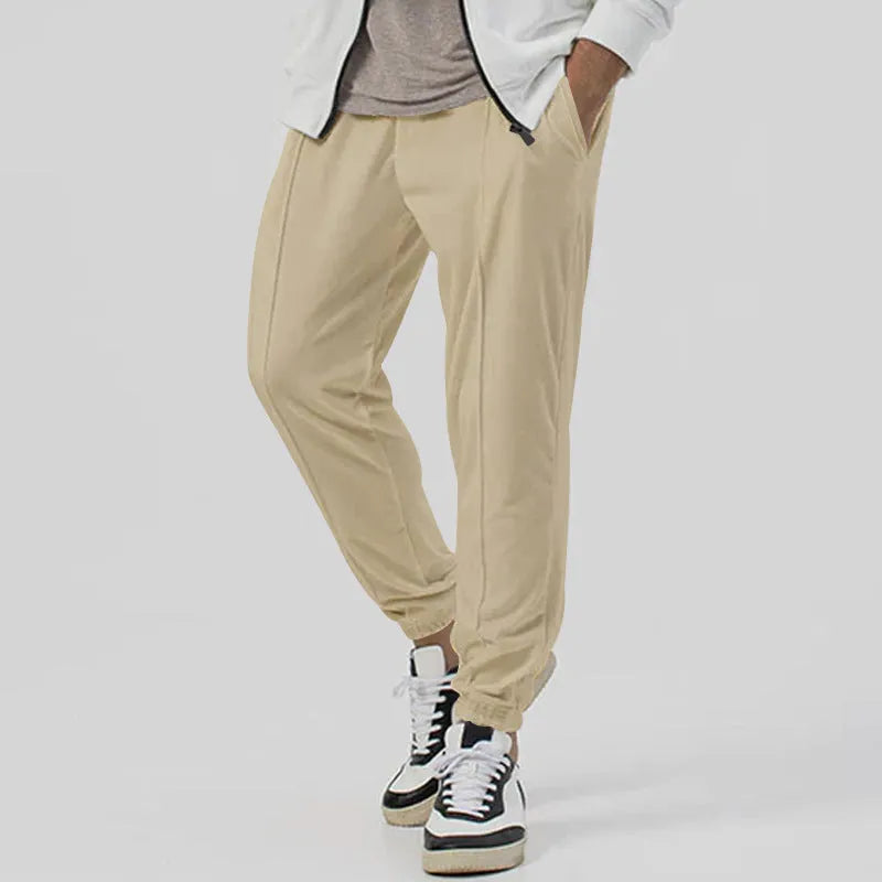 Man wearing grey loose tapered track sweatpants with a micro-elastic cotton blend fabric.