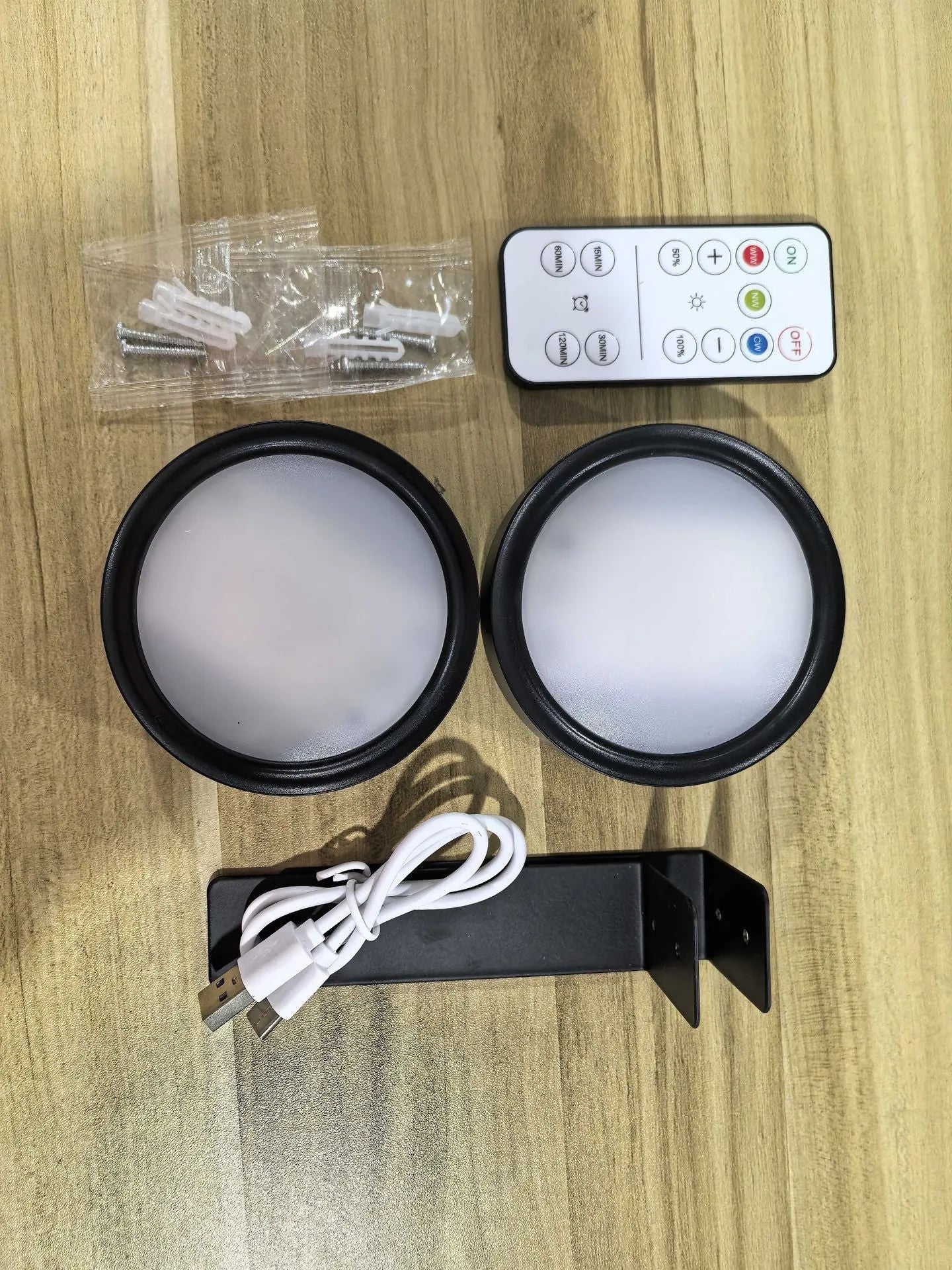 Black magnetic wireless LED lamp with remote control mounted next to a painting on a wall.