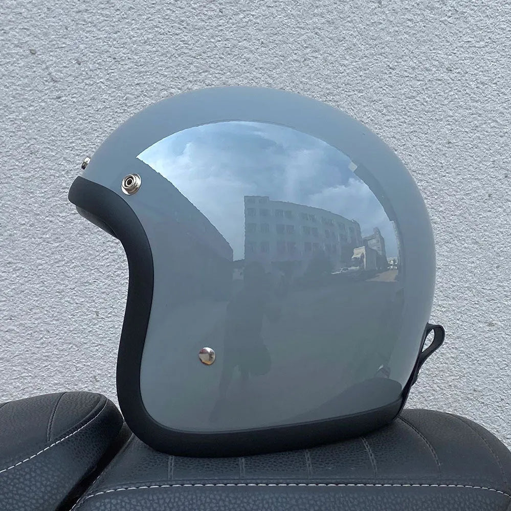 Retro-style open-face motorcycle helmet in fibreglass, shown in a choice of colours including Cement Grey and Matte Black Flower.