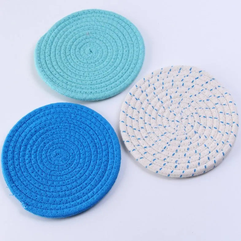 Three round cotton cord coasters in blue, measuring 18cm diameter, on wooden table