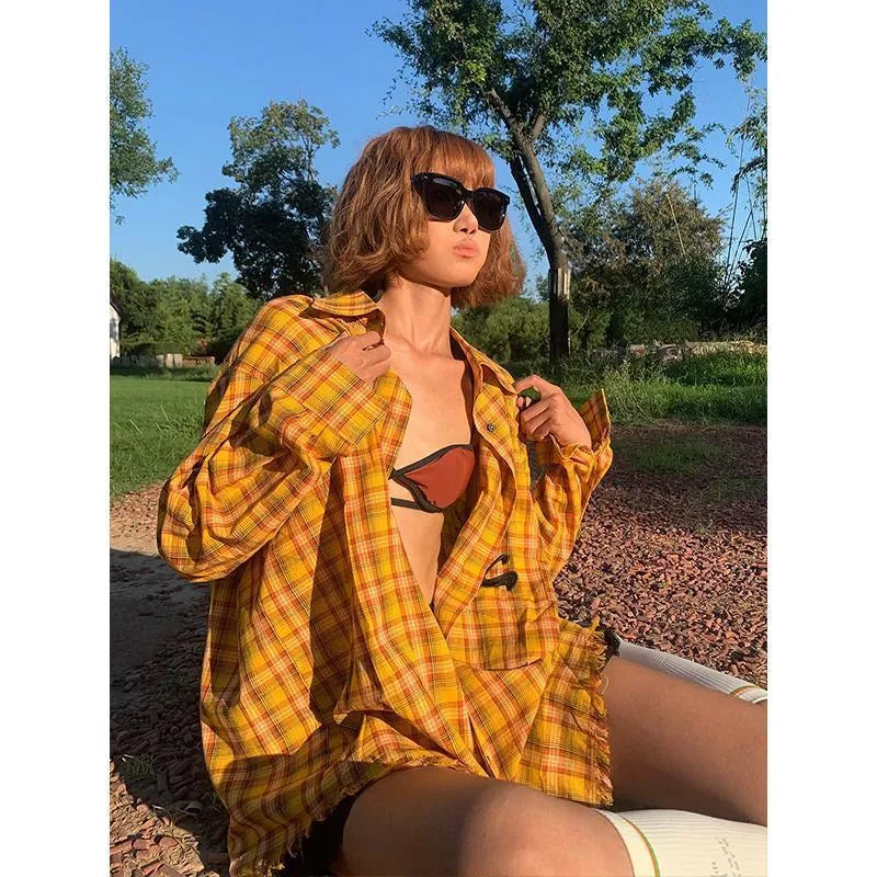 Dopamine yellow and black plaid shirt with a loose cardigan style fit on a hanger.