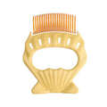 Green shell-shaped pet grooming comb with bent wire bristles and an anti-slip plastic handle.