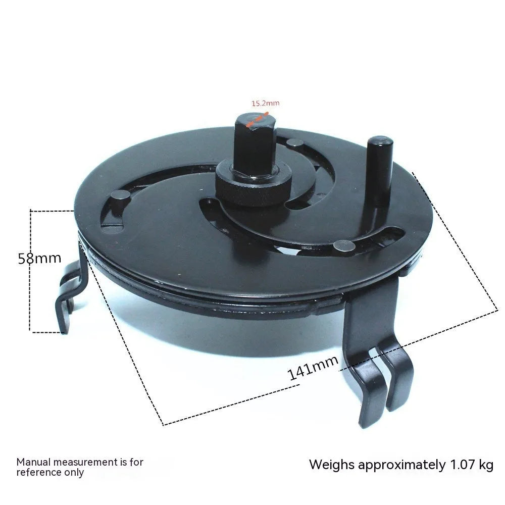 Black disc-shaped steel petrol tank cap removal wrench on a workshop surface