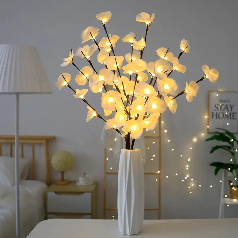 Pink fabric and plastic LED Phalaenopsis orchid branch light, 65cm long, on a table providing warm white ambient glow.