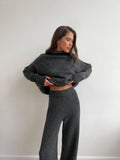 Women's dark grey acrylic knitted lounge suit with side-slit sweater and matching trousers on a hanger.