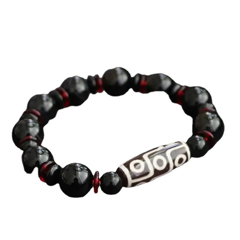 Hand-woven black agate dzi bead bracelet with geometric chalcedony beads on a wrist.