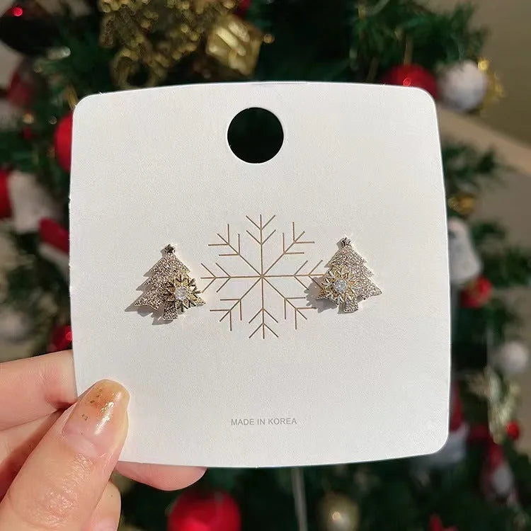 Pair of rotatable Christmas tree stud earrings with rhinestone snowflake detail in gold on a white background