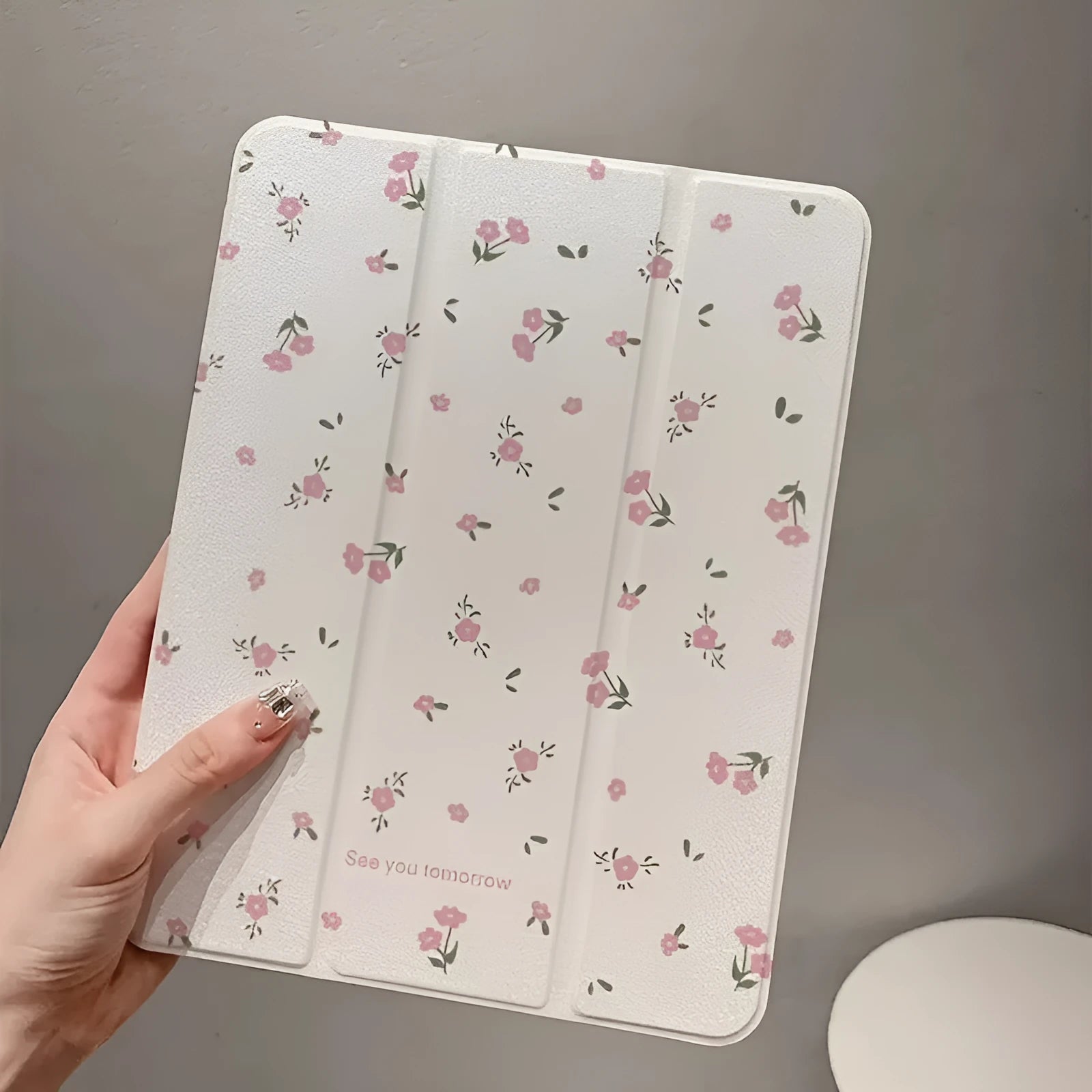 Transparent tri-fold Apple iPad case with cartoon floral print showing magnetic stand function.