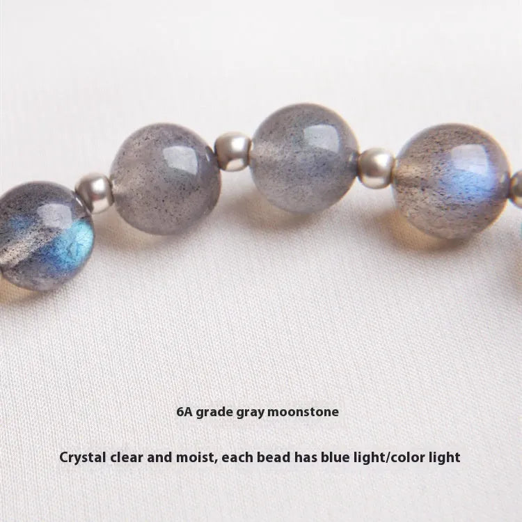Close-up of a women's 925 sterling silver bracelet with a grey moonstone bead and a zodiac animal charm.