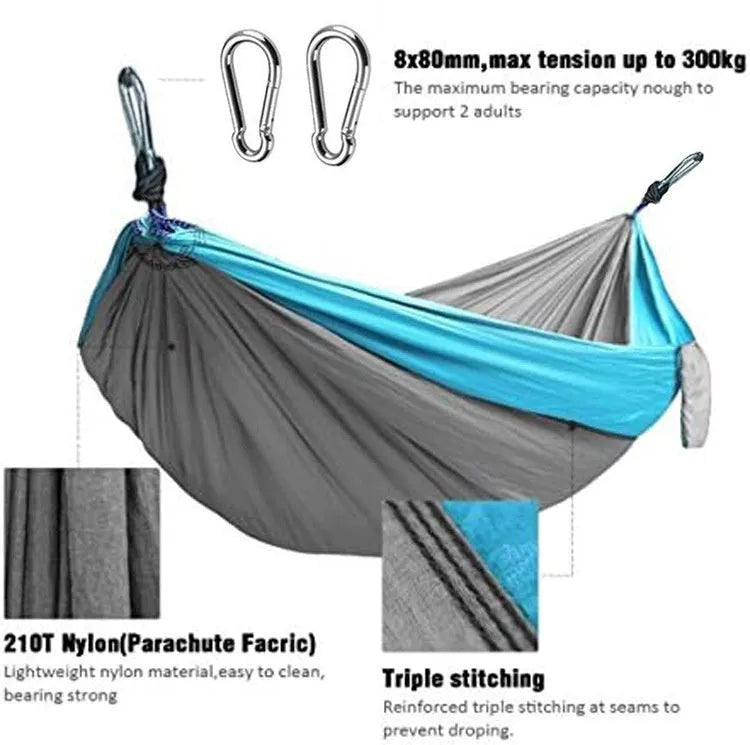 Blue parachute nylon camping hammock hung between two trees, showing its full 270cm length and attachment carabiners.