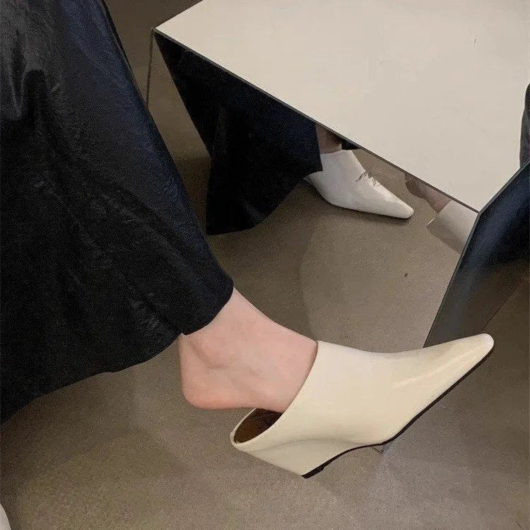 Women's black Wind Wedge closed toe half slippers with PU upper on a wooden floor.