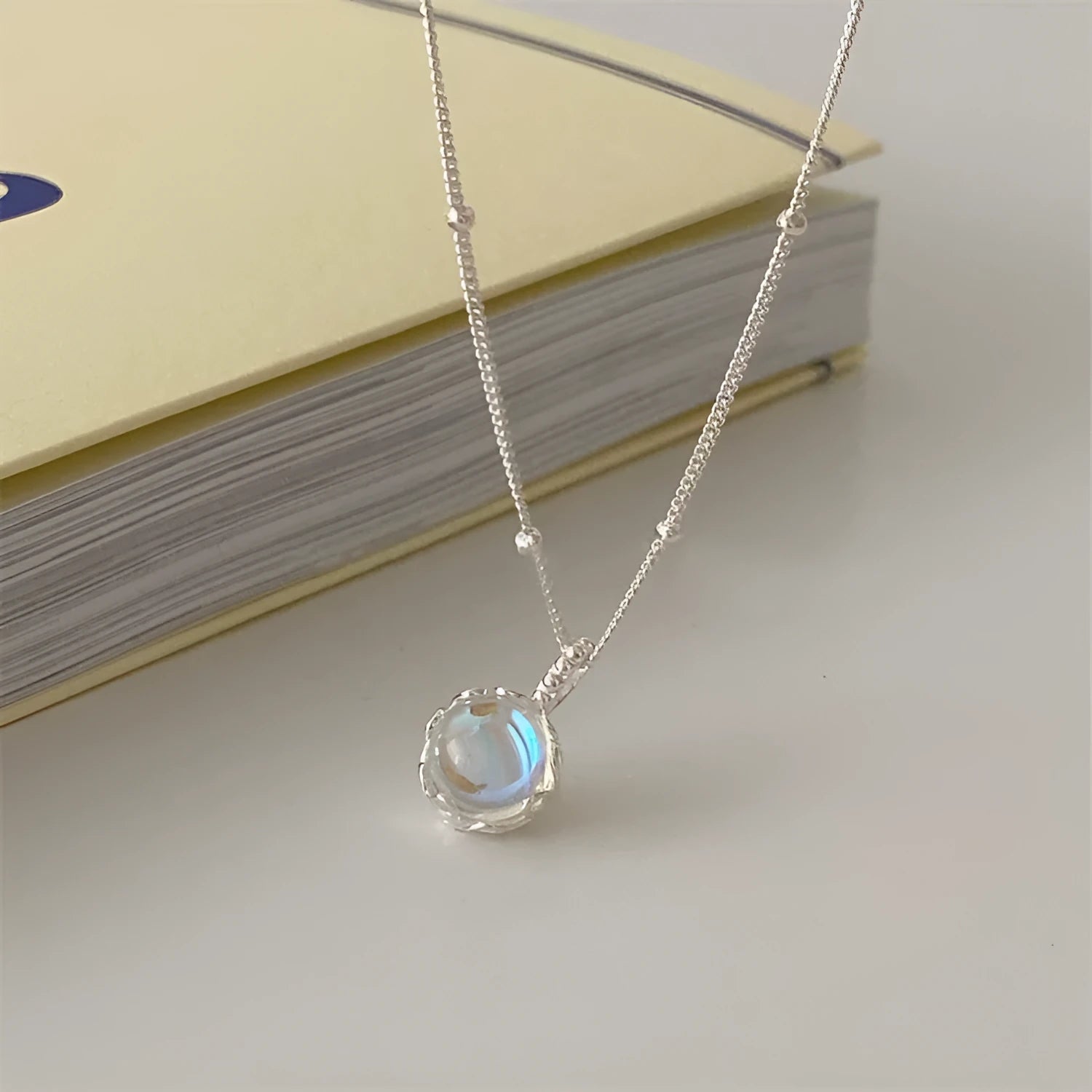 Women's silver necklace with a geometric stone pendant on a curb chain.