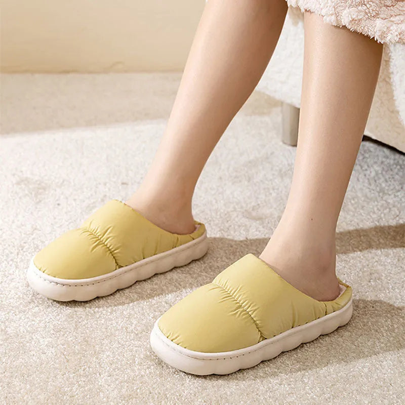 Blue down cotton winter slippers with a thick rubber sole and plush lining, shown on a wooden floor.