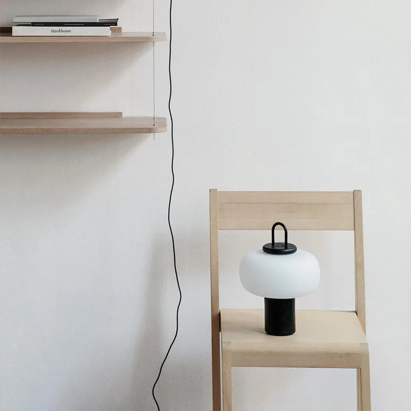 Minimalist Japanese designer glass bedside table lamp with warm light for a child's room.