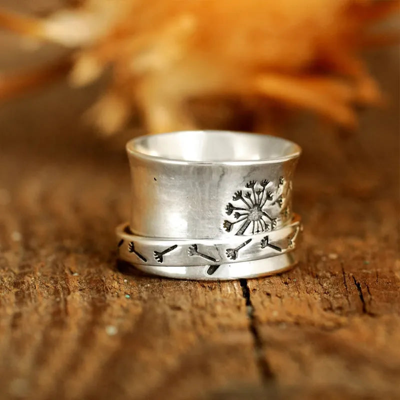 Silver rotating flower ring with movable petals on a finger, showing the kinetic jewellery design