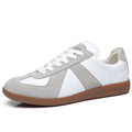 White low-top retro sneakers with round toe and lace-up front on a flat rubber sole.