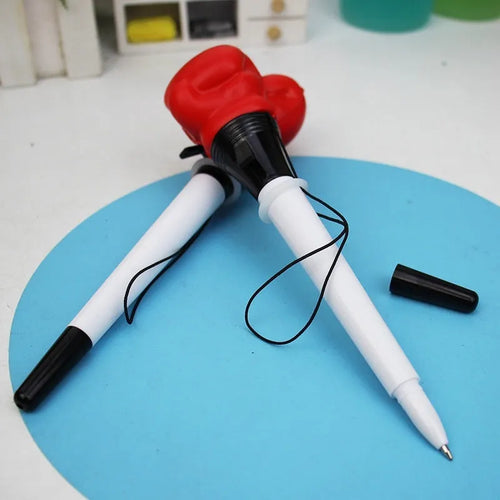 Boxing pressure pen ejection press stationery toy with four black pens on a desk.