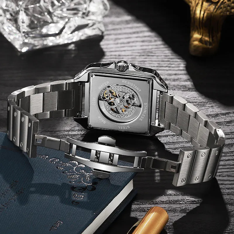 Men's square-faced automatic watch with diamond studs on a stainless steel bracelet.