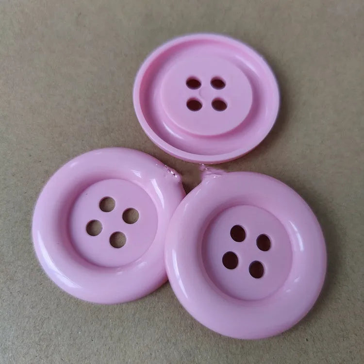 Oversized round edge plastic button with four holes in various colours and diameter sizes