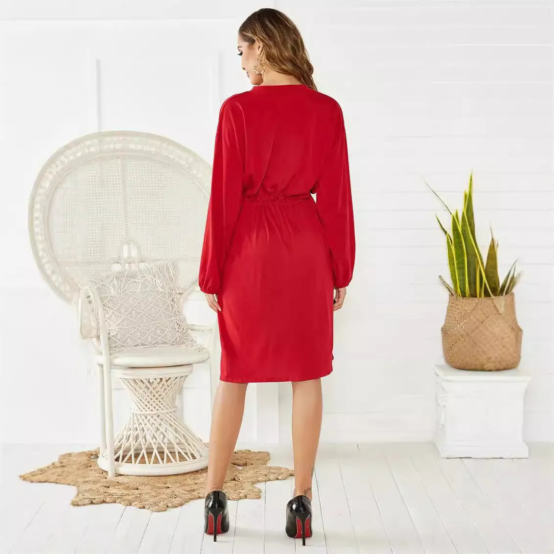 A woman's solid-colour A-line dress with long sleeves, elastic cuffs, an elastic waist, and a cinched belt.
