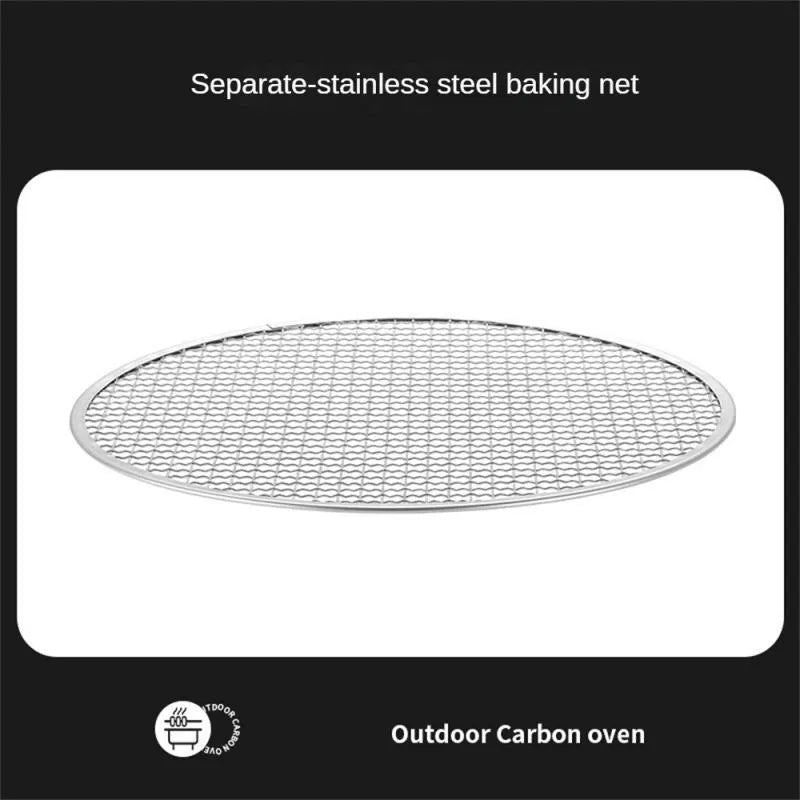 Portable stainless steel barbecue grill with detachable parts on a grassy outdoor surface.