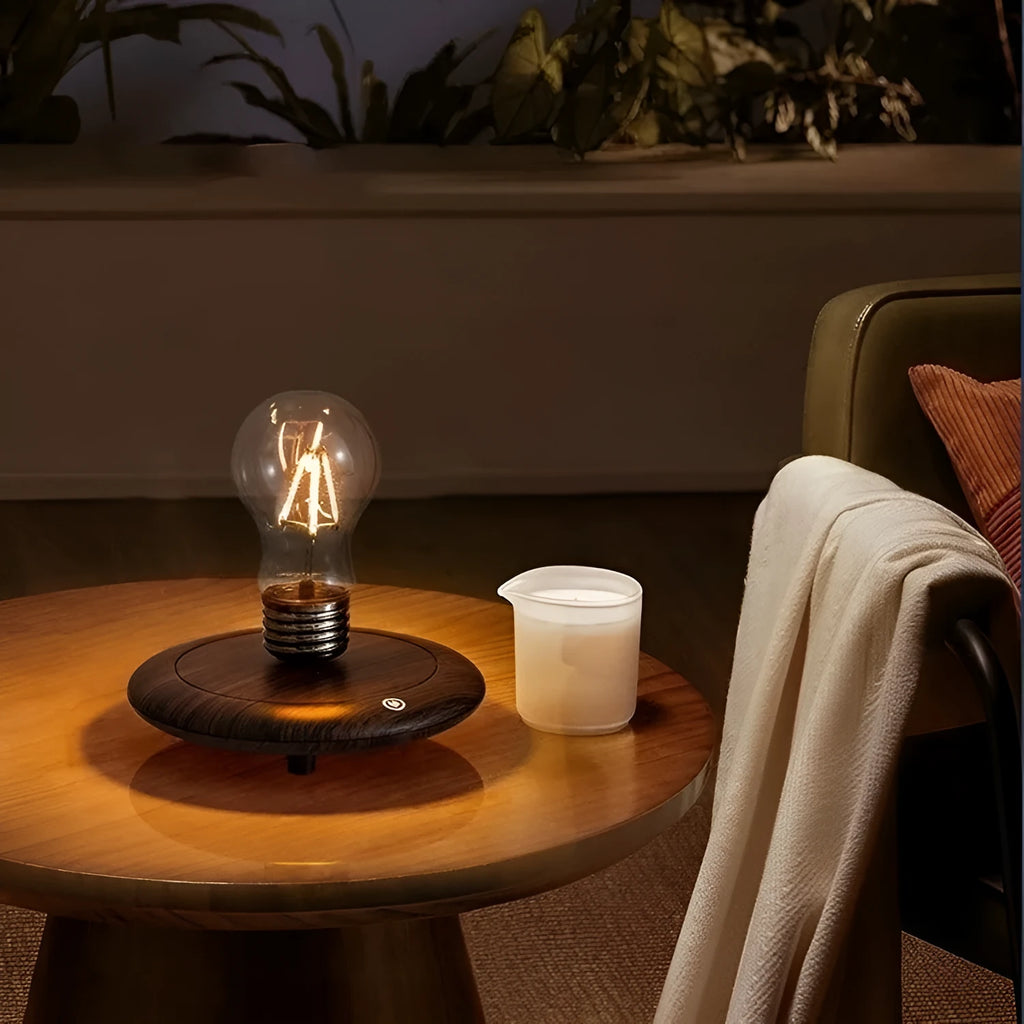 Small black suspension bulb night lamp with an iron art base on a wooden desk.