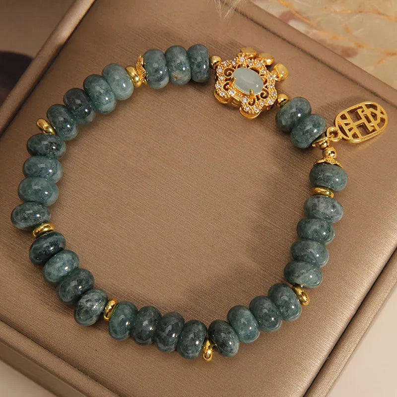 Close-up of a women's bracelet with green emerald jade and silver alloy abacus beads and a safety lock clasp.