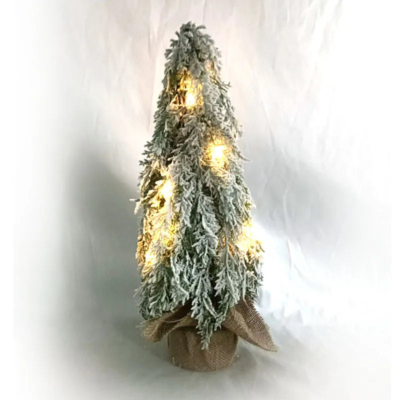 Small 24-inch plastic Christmas tree with LED lights and snow-covered branches on desktop
