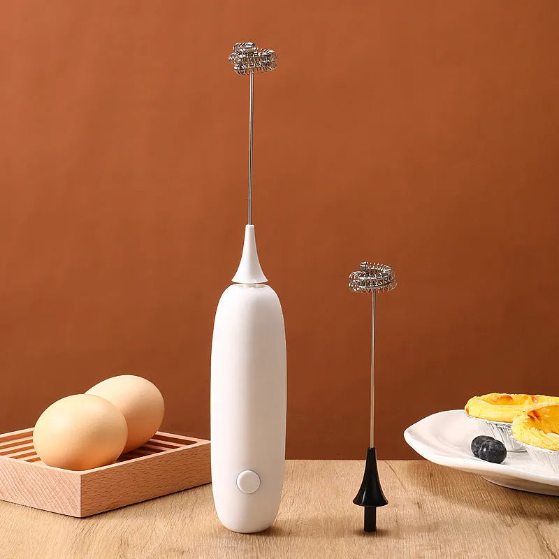 A handheld electric milk frother and blender in black and white colours on a kitchen counter.