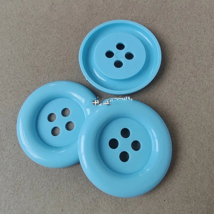 Oversized round edge plastic button with four holes in various colours and diameter sizes
