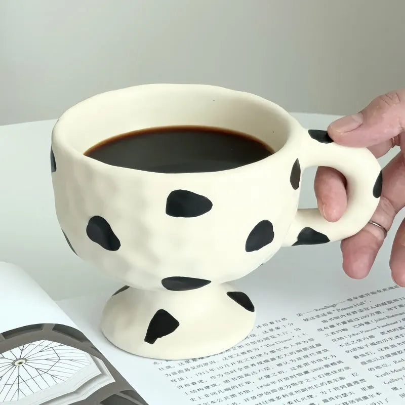 Handmade irregular solid colour ceramic mug on a table, showing its unique shape.