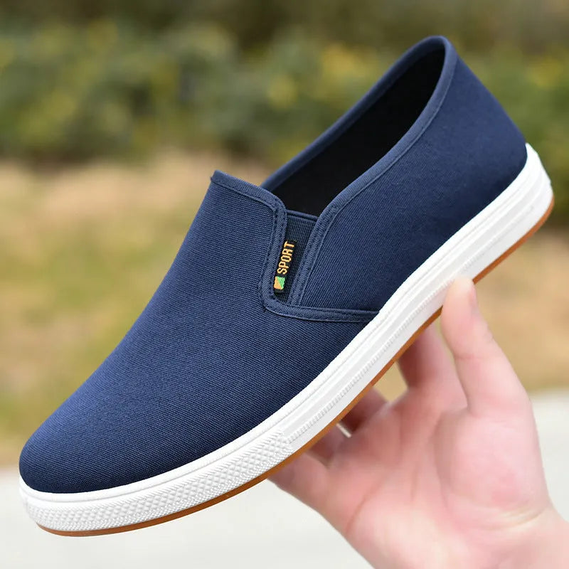 Men's low-top black canvas slip-on shoes with round toe and shallow mouth on a composite sole.