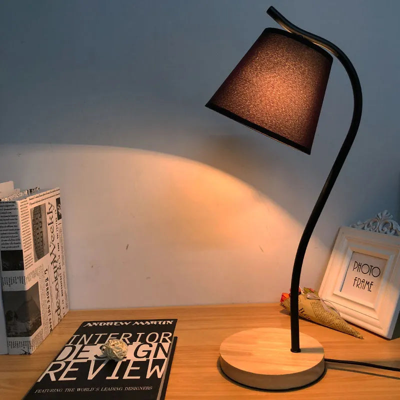A simple modern Nordic style LED desk lamp with a dimmer switch on a desk.