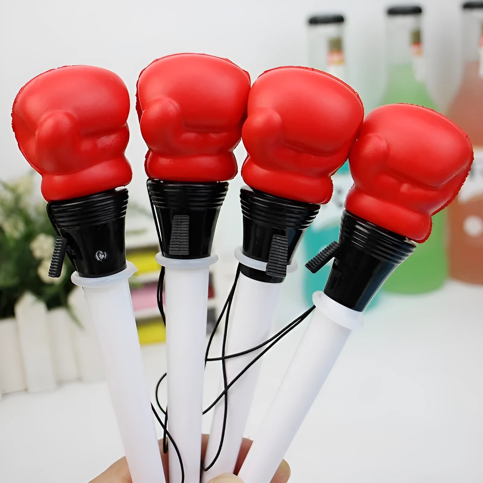 Boxing pressure pen ejection press stationery toy with four black pens on a desk.