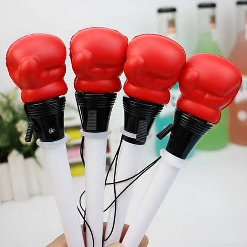 Boxing pressure pen ejection press stationery toy with four black pens on a desk.