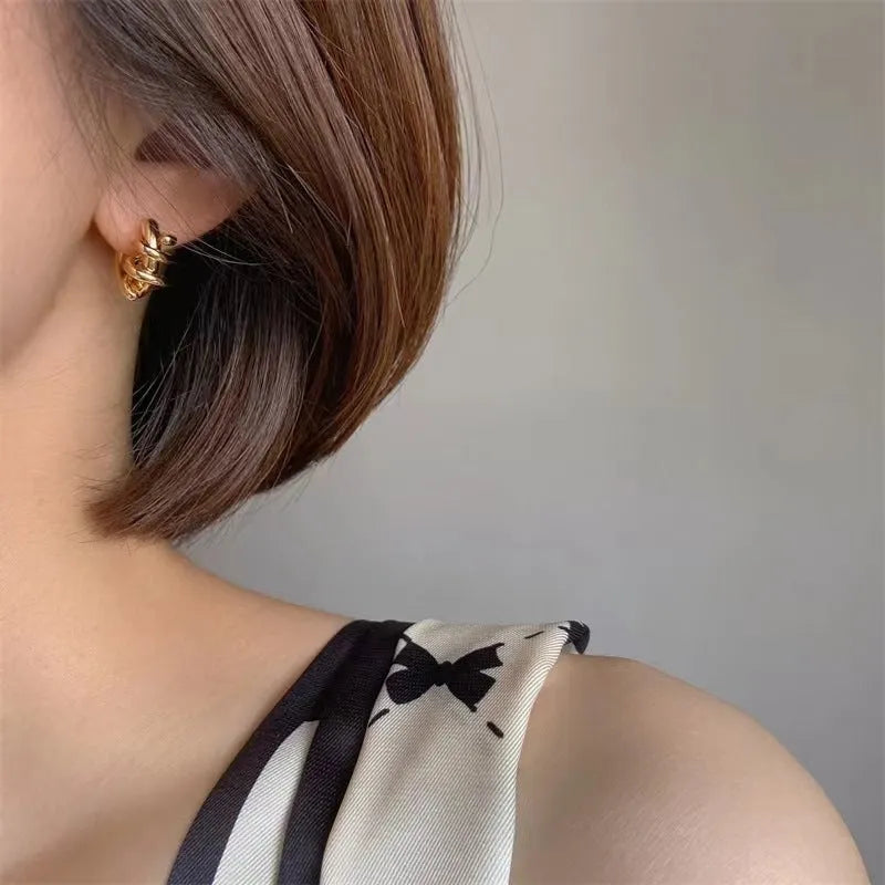 Spiral wound ear clip frosty style geometric earrings in gold colour on white background