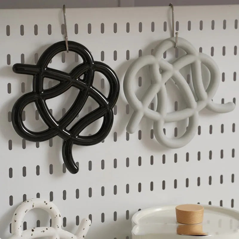 Modern irregular-shaped ceramic heat proof mat in grey on a wooden table protecting it from a hot pan.
