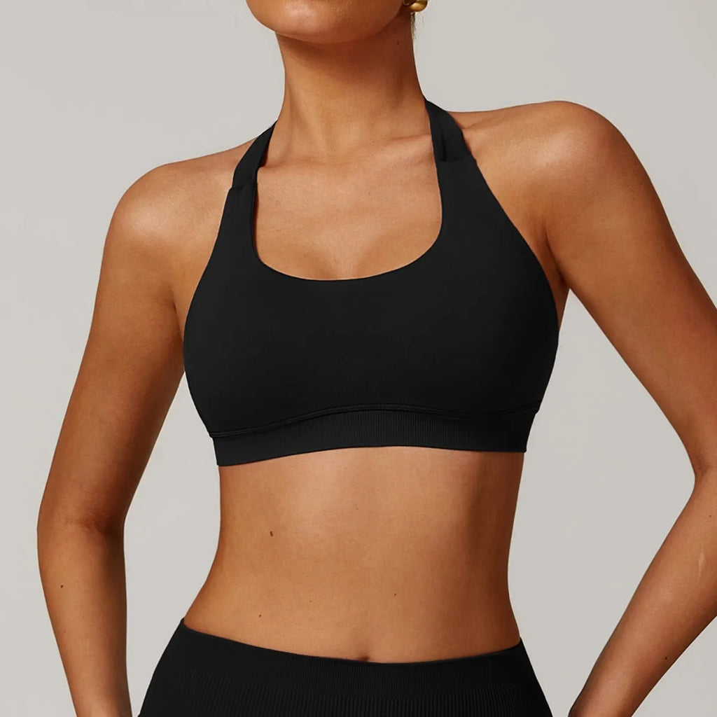 Women's black halter neck sports bra with removable padding on a grey background, showing back and front detail.