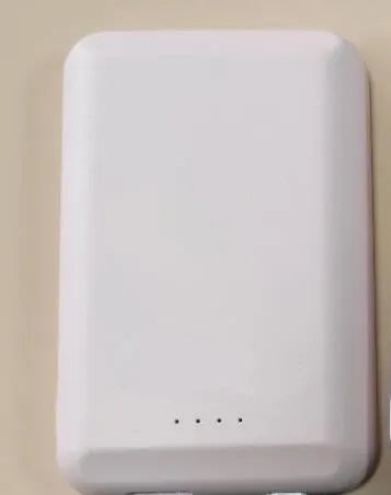 A black magnetic wireless power bank attached to the back of an iPhone for charging.