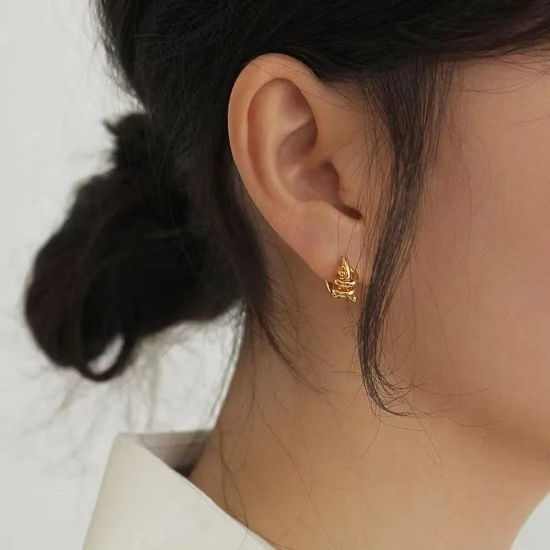 Spiral wound ear clip frosty style geometric earrings in gold colour on white background