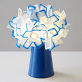 Nordic style decorative table lamp in a choice of colours including black, blue, and orange on a wooden surface.