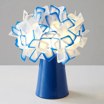 Nordic style decorative table lamp in a choice of colours including black, blue, and orange on a wooden surface.