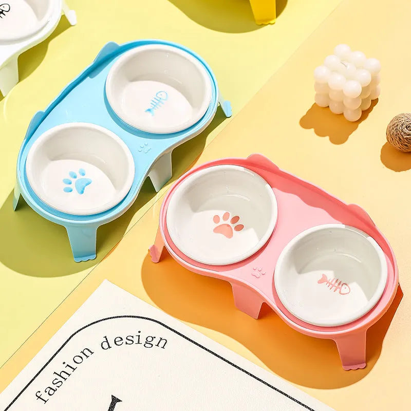 Blue ceramic cat food and water bowl set on a white elevated plastic stand with hook design.