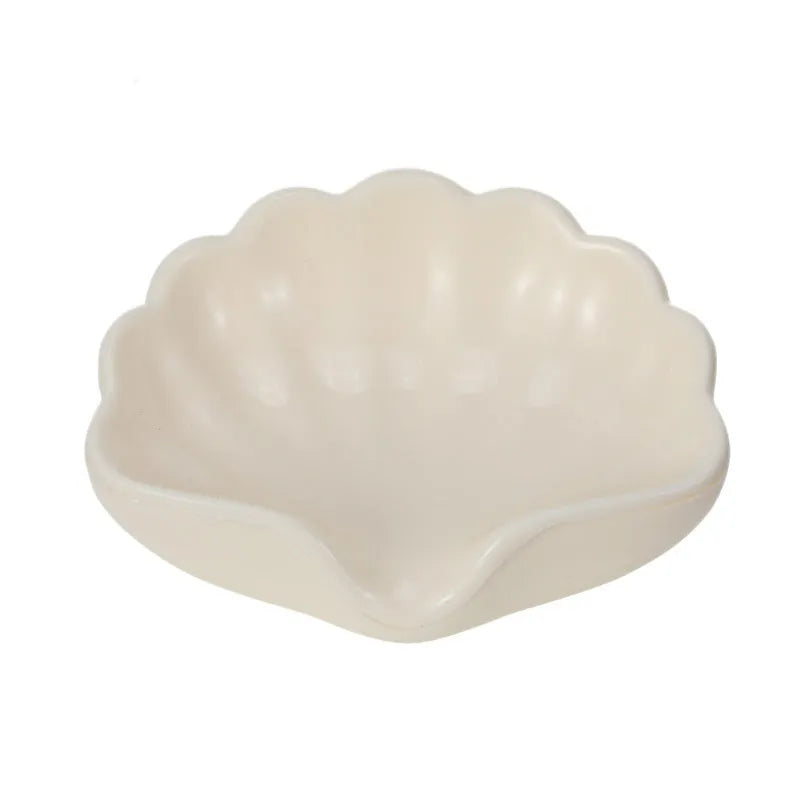 White or pink plastic shell-shaped soap dish for bathroom sink or shower.