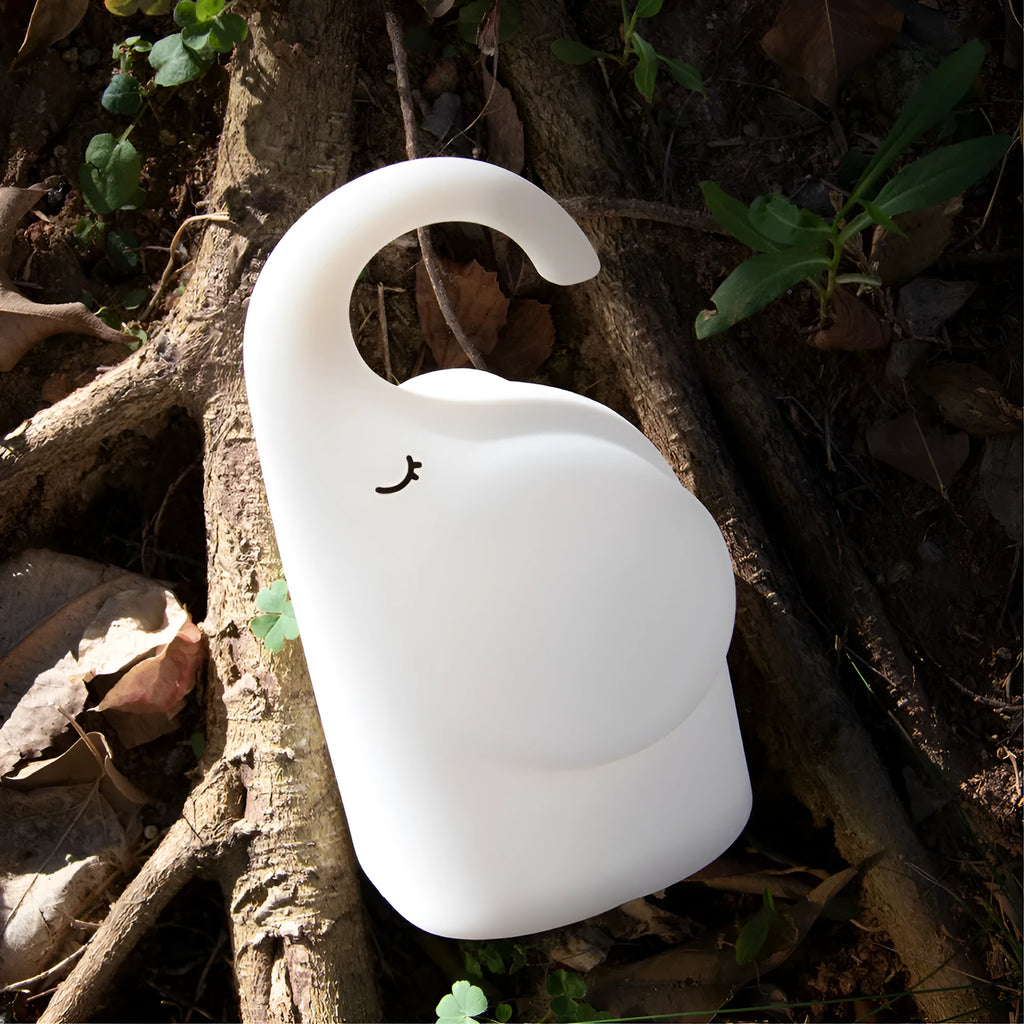 DOMI Elephant shaped silicone night light on a table showing its compact size and soft glow.